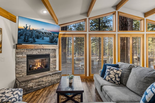 Cozy up by the warm fireplace while enjoying forest views through expansive windows in this beautifully designed living space.