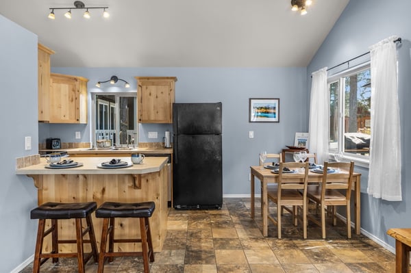 Step into your open kitchen and dining area, where warm wood tones meet soothing blue walls. Gather around the breakfast bar or dining table as natural light streams through white curtains, creating the perfect backdrop for memorable meals together.