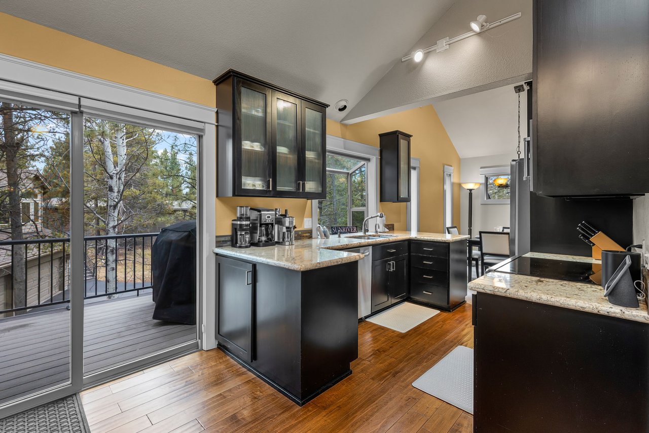 Your fully-equipped kitchen awaits with granite countertops, stainless appliances, and sunny balcony access for morning coffee with treetop views.