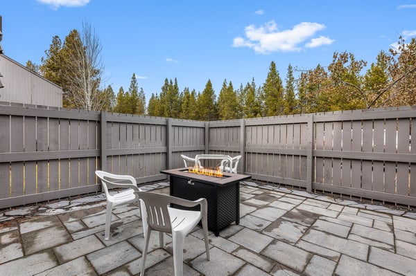 Gather around your private fire table on this enclosed patio, where cozy evenings unfold under open skies surrounded by towering evergreens.