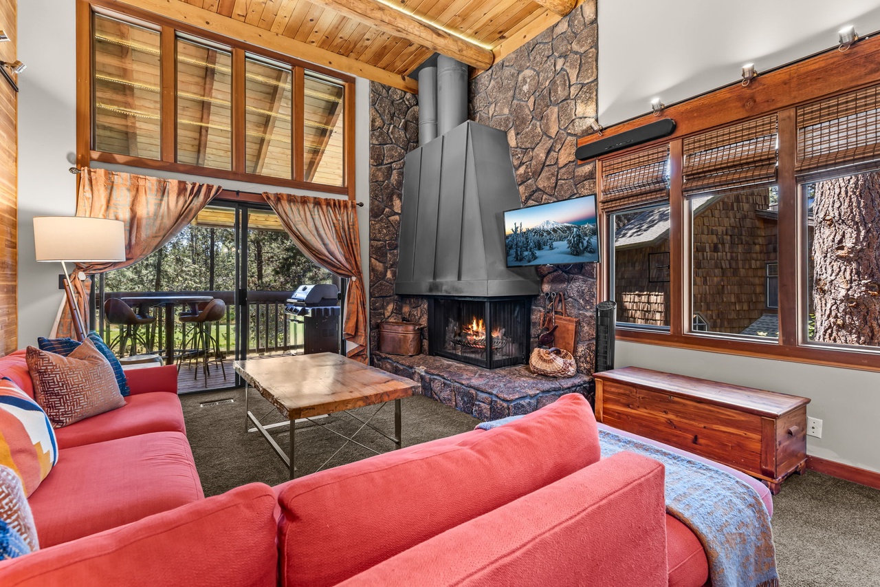 Curl up in your cozy living room with soaring wood-beamed ceilings, a crackling stone fireplace, and peaceful forest views through every window.