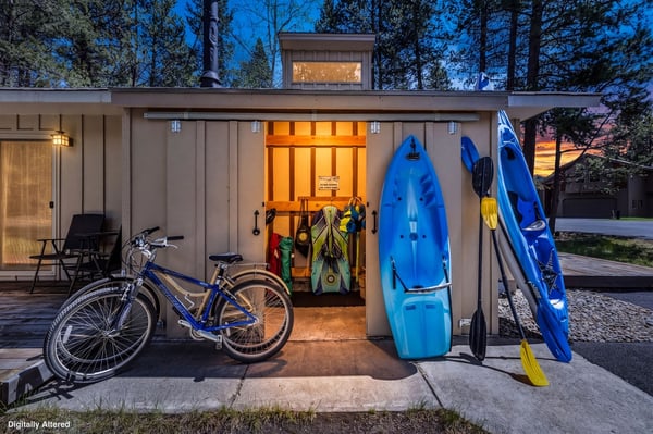 A well-lit storage shed with kayaks, bikes, and outdoor gear—ready for your next adventure in the surrounding forest.
