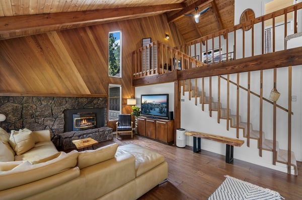 Sink into plush seating by the stone fireplace while warm wood beams frame your mountain retreat. The open loft design invites you to unwind with cozy ambiance and rustic elegance.