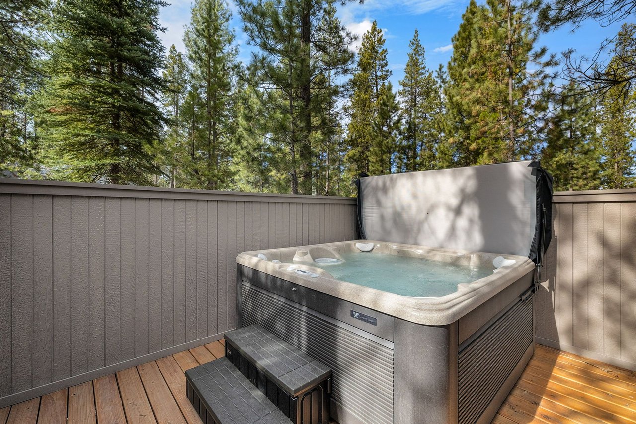 Slip into your private hot tub surrounded by towering pines, where warm bubbling water meets forest tranquility on this secluded deck.