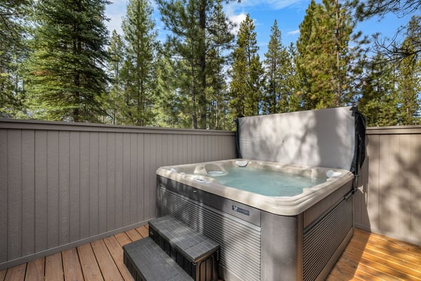 Slip into your private hot tub surrounded by towering pines, where warm bubbling water meets forest tranquility on this secluded deck.