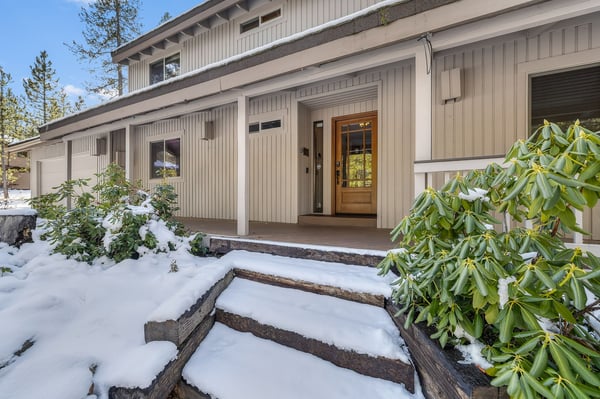 Winter wonderland entrance with snow-dusted steps and evergreen landscaping leading to this charming mountain retreat.