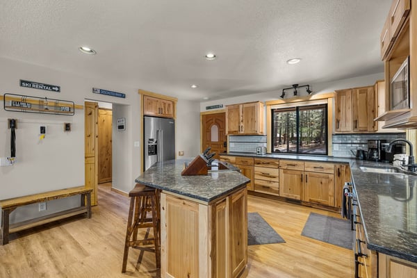 Gather around this spacious kitchen island while you prepare meals together, surrounded by warm wood cabinets and granite countertops.