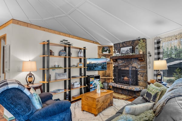 Unwind in your cozy mountain retreat featuring a stone fireplace, plush seating, and rustic charm perfect for evening relaxation.