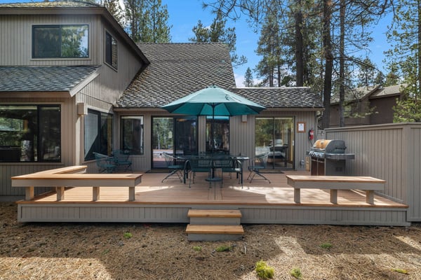 Modern cabin retreat nestled among towering pines, featuring a spacious deck with outdoor dining and BBQ for memorable forest getaways.