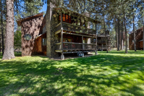This charming rustic cabin stands amid towering pines and lush green lawns, offering a peaceful forest retreat with dual-level balconies perfect for morning coffee and starlit evenings.