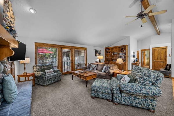 Settle into your spacious living room with plush seating, warm wood accents, and natural light streaming through sliding glass doors—perfect for unwinding after a day of adventure.