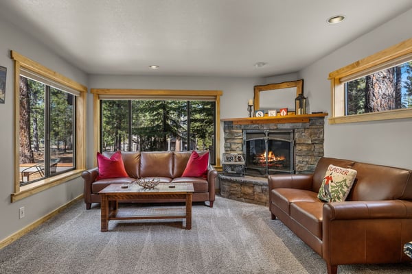 Sink into rich leather seating beside your crackling stone fireplace, surrounded by windows showcasing towering pines.