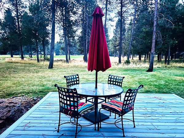 Savor your morning coffee at this charming outdoor dining space, perfectly positioned among towering trees for peaceful meals.