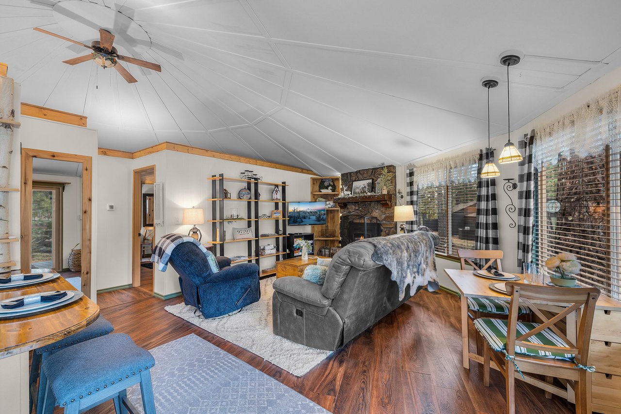 Unwind in your spacious living area featuring cozy leather seating, rustic stone fireplace, and warm wood accents throughout this mountain retreat.